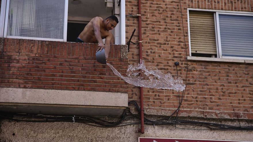 Un vecino arroja agua desde un balcón para mojar sin ser mojado.