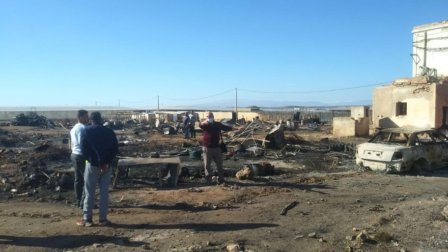 Un grupo de hombres observa cómo ha quedado el asentamiento tras el incendio