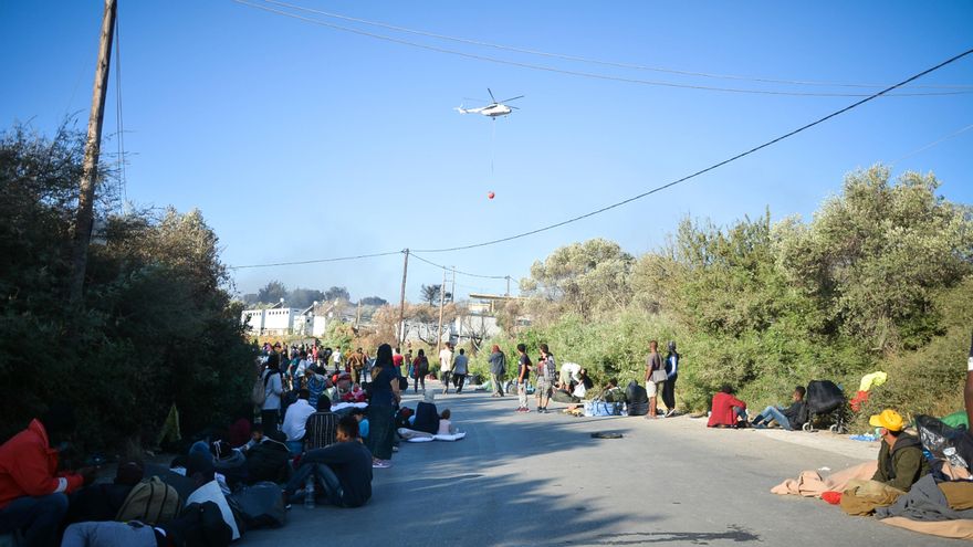 Residentes del campo de refugiados después del incendio de evacuación en el campo de Moria miran hacia uno de los aviones extintores de incendios.