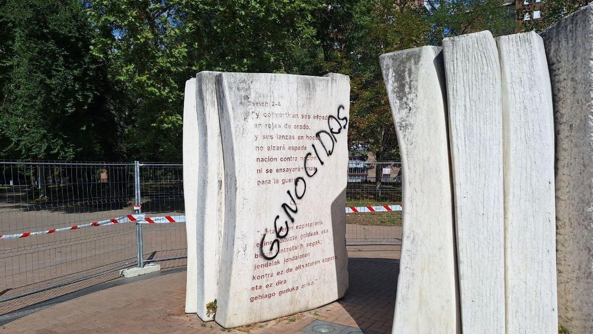 Una pintada que dice "Genocidas", sobre la escultura, situada en el barrio de Judimendi
