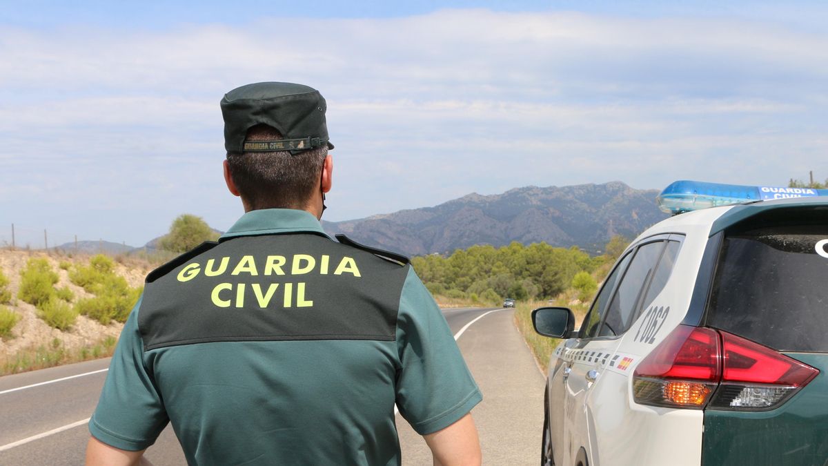 Archivo - Un agente de la Guardia Civil junto a un vehículo en una carretera.