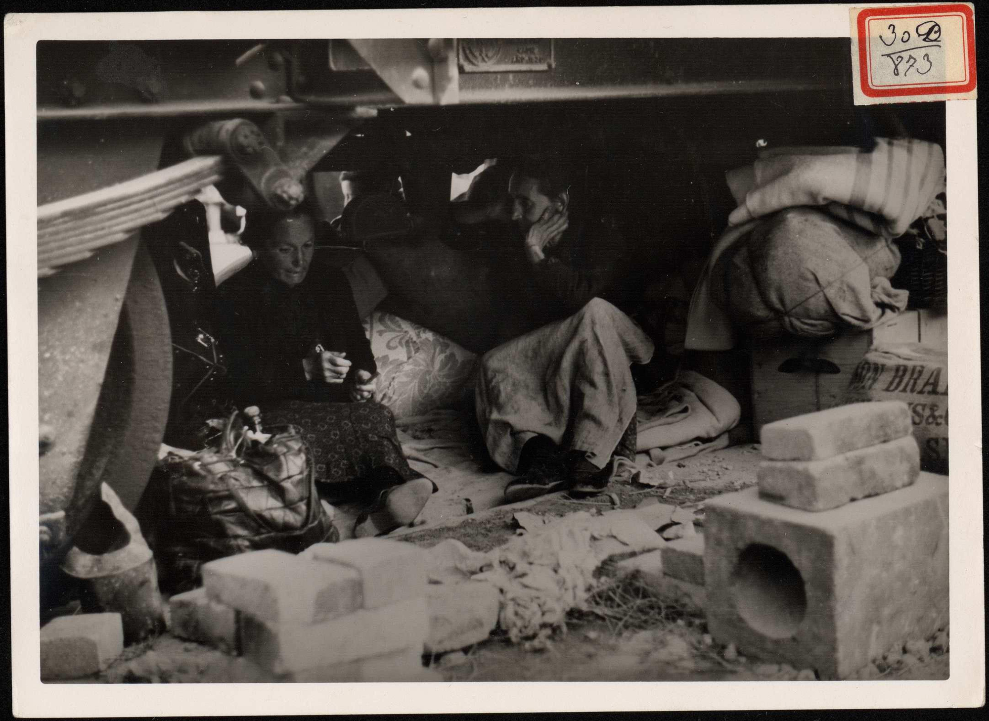 "Refugio de hombres y mujeres bajos los vagones del ferrocarril del puerto, se han instalado dos viejecitas es espera de su traslado a su suelo de Guipúzcoa. 8 de septiembre de 1937. | Biblioteca Nacional de España