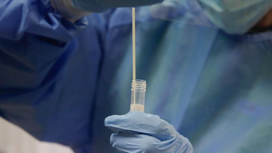 Archivo - Una trabajadora sanitaria sostiene una probeta con una prueba PCR