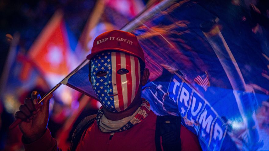 Un simpatizante de Donald Trump fue registrado este martes al vestir una careta con la bandera estadounidense y una gorra que dice "Mantén (América) grandiosa", en el icónico café Versailles de la Calle Ocho, en Miami (Florida, EE.UU.). EFE/Giorgio Viera
