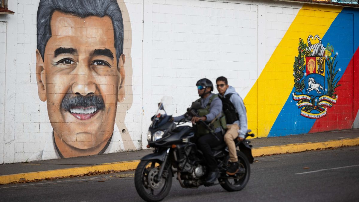 Personas transitan frente a un mural del presidente de Venezuela, Nicolás Maduro, este domingo en Caracas (Venezuela). EFE/ Ronald Peña R