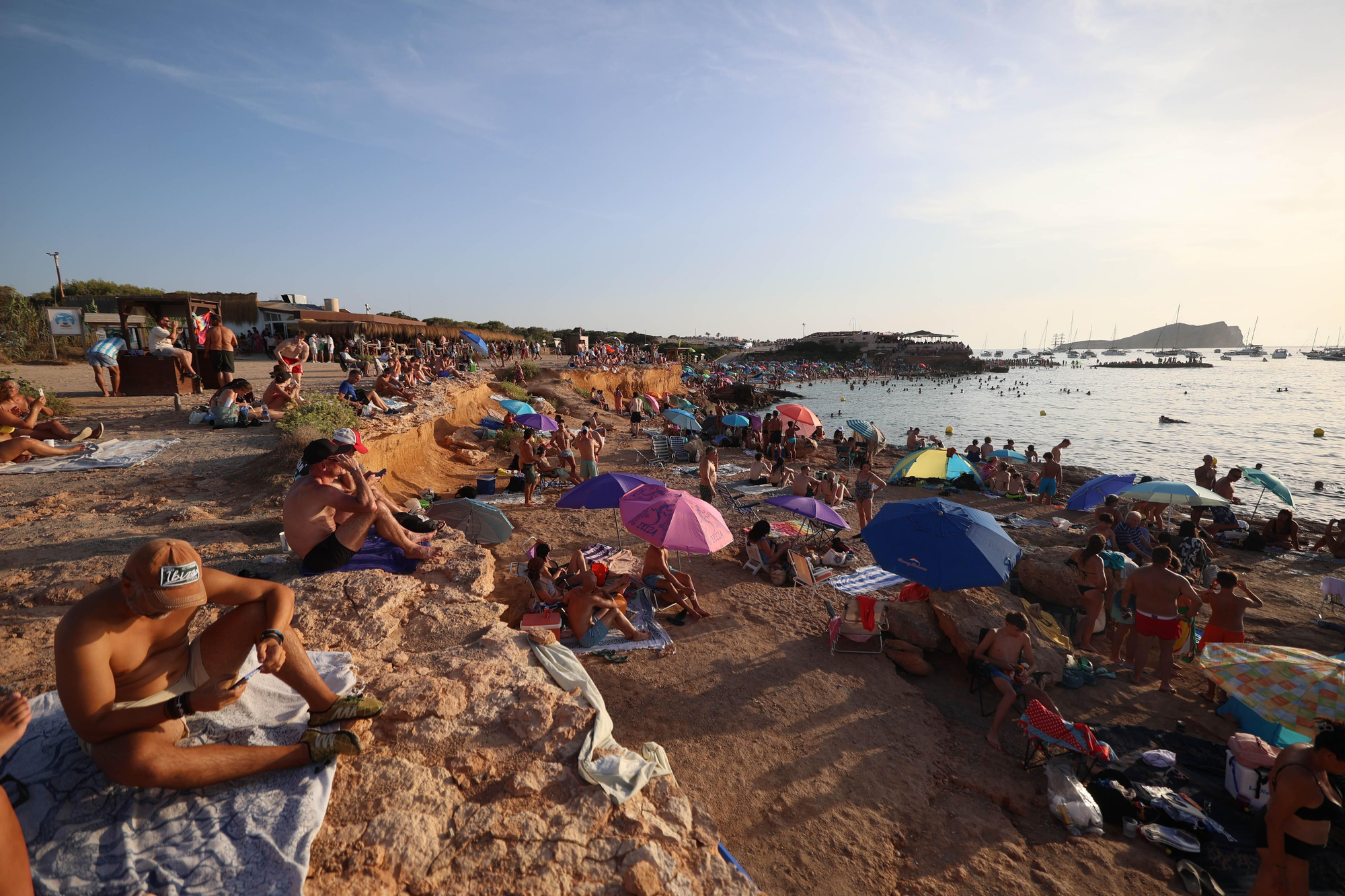 Centenares de bañistas y curiosos se agolpan en la arena de Cala Comte para prepararse minutos antes del esperado inicio del eclipse parcial de sol