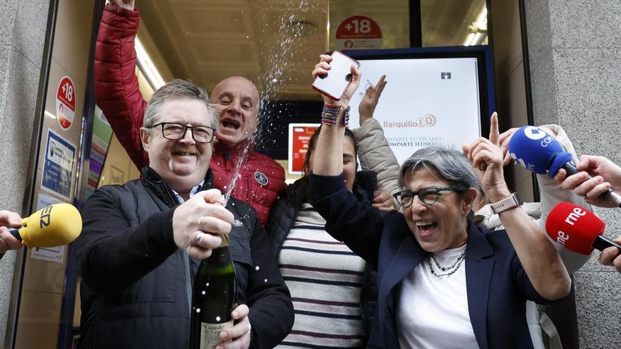 Varias personas celebran a las puertas de la administración de loterías del número 10 de la calle Barquillo, en Madrid, donde se ha vendido íntegramente el 70.048, el segundo premio del Sorteo Extraordinario de la Lotería de Navidad.