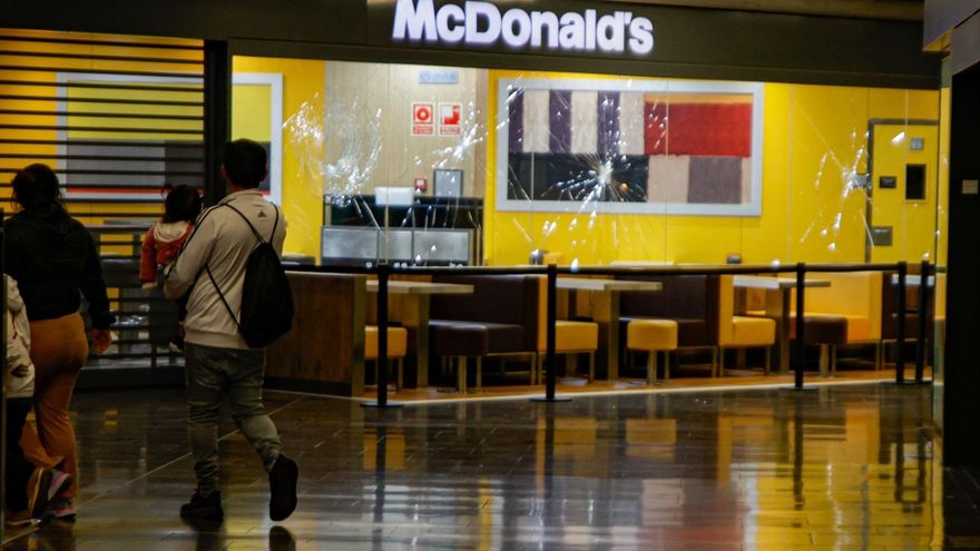 Dos personas pasan delante del escaparate del McDonald's con los cristales rotos en el centro comercial Màgic Badalona, a 27 de marzo de 2024, en Badalona, Catalunya (España)
