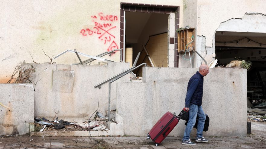 Un hombre pasa con una maleta junto a un edificio golpeado por un misil iraní.