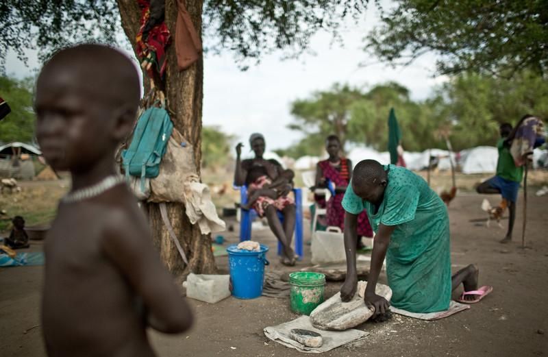 Las mujeres tienen que moler el sorgo que reciben del Programa Mundial de Alimentos para que los más pequeños puedan comérselo. Algunas no pudieron coger el mortero cuando huyeron de sus casas y tienen que ir turnandoselo para poder cocinar. Martha Nyandit (42 años), madre de 6 hijos. Huyó de los combates en Bor, estuvo 17 días escondida en una isla del río Nilo. Llegó a Mingkaman en enero 2014 donde se enteró que su marido había muerto. No sabe dónde está el resto de su familia y no tiene una tienda dónde refugiarse cuando llueve. Llegó sin nada y depende de que las otras mujeres le presten sus cazos para poder cocinar.  El campo de desplazados de Mingkaman, en Awerial, se ha convertido en refugio para casi 100.000 personas, principalmente de la etnia dinka, que huyeron de los enfrentamientos violentos en el estado de Jonglei, principalmente de la ciudad de Bor. Las personas que llegan necesitan agua, comida y un techo dónde refugiarse.  Sudán del Sur afronta una grave crisis a causa de la violencia que se desató en diciembre de 2013 entre las fuerzas leales al presidente Salva Kiir, y los combatientes aliados al ex vicepresidente Riek Machar. Cerca de un millón de personas han tenido que abandonar sus hogares a causa de los enfrentamientos y se han quedado sin medios propios para alimentarse. Un tercio de la población sufre inseguridad alimentaria./Pablo Tosco/Oxfam Intermón