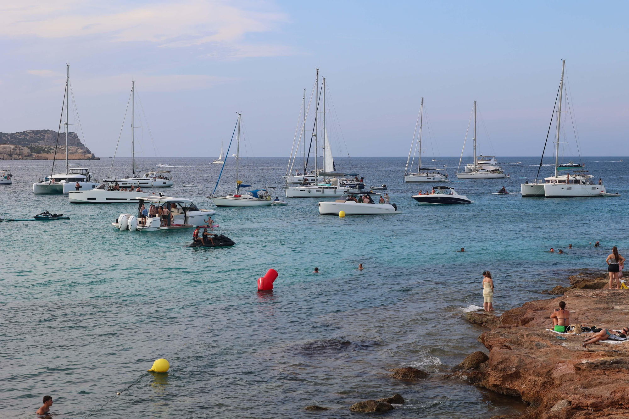 Los bañistas observan las fiestas a bordo de algunas embarcaciones frente a Platges de Comte