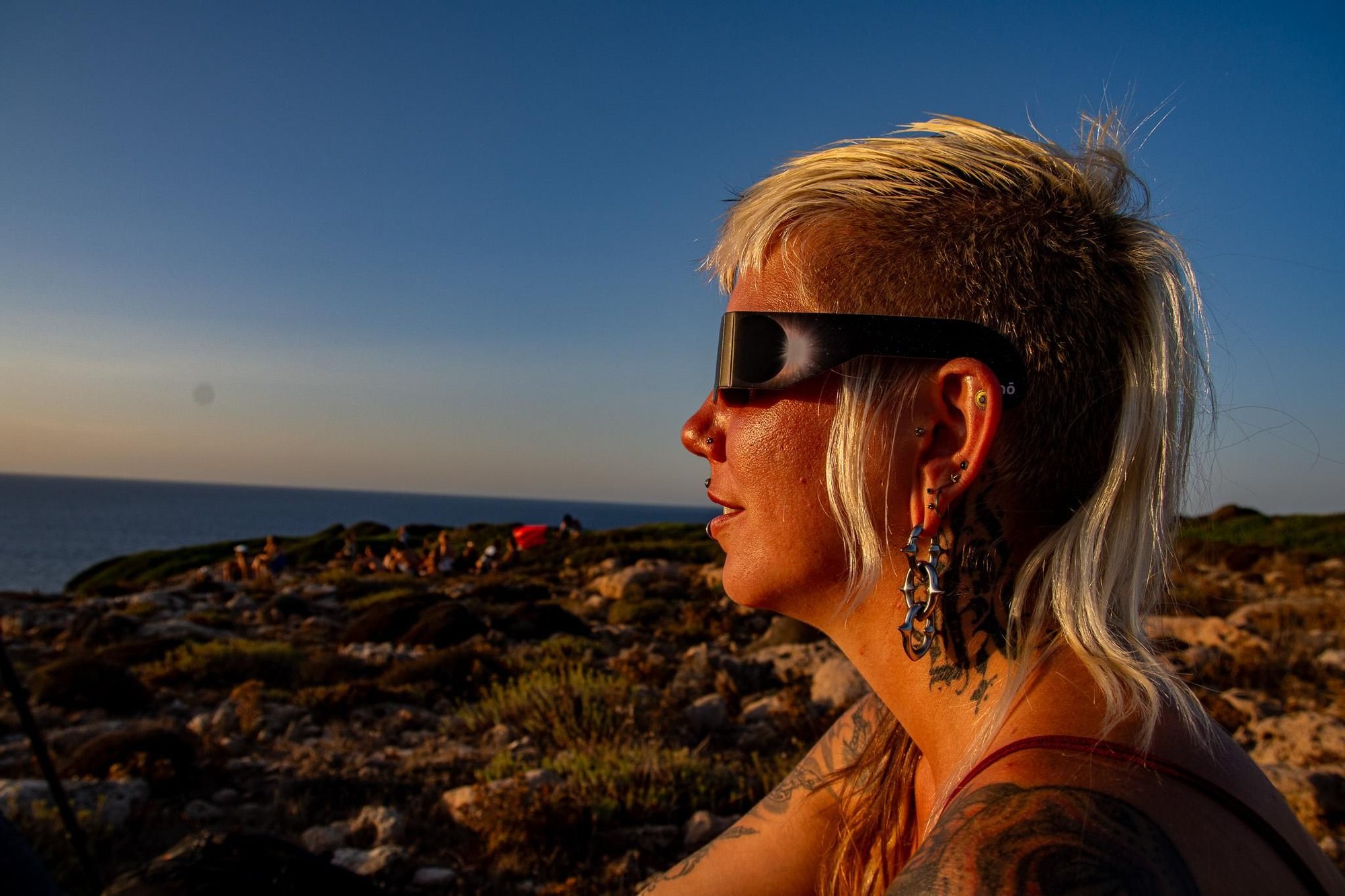 Una espectadora observa el eclipse con gafas homologadas desde el litoral de Menorca