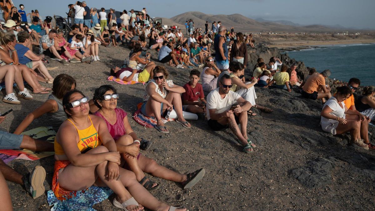 Varias personas contemplan desde la localidad de El Cotillo, en la isla de Fuerteventura, el eclipse solar de este miércoles.