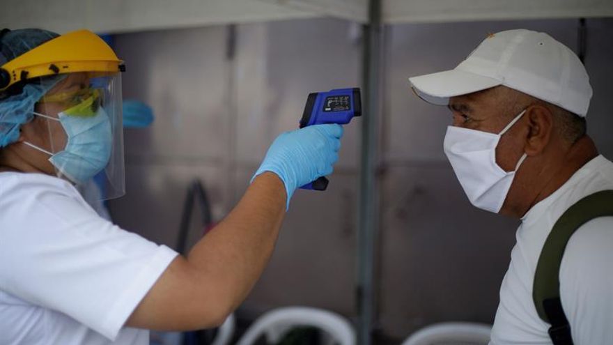 Una enfermera (i) toma la temperatura a un hombre durante una jornada de prevención de COVID-19, en San Salvador (El Salvador).