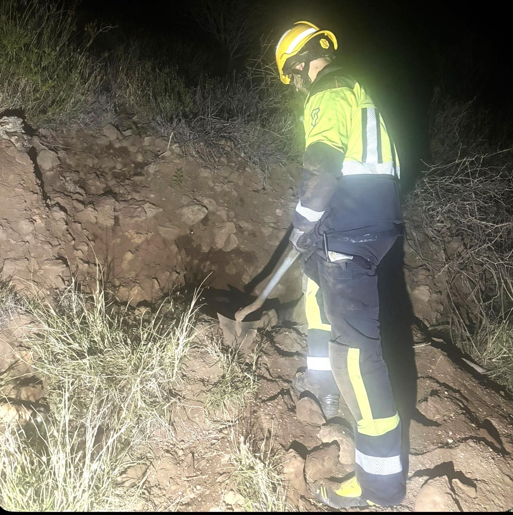 Un bombero ensanchando el hueco de la madriguera en la que quedó atrapado el  perro.