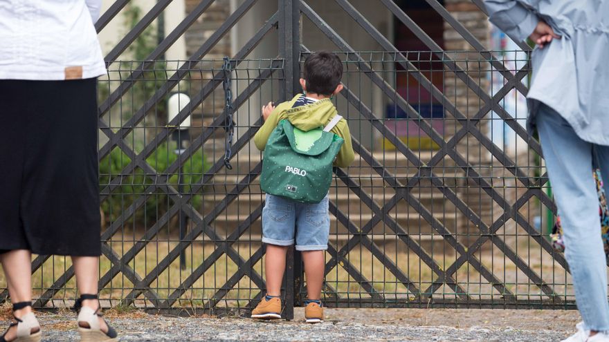 Un niño se asoma a las puertas del colegio.