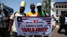Ciudadanos liberianos sostienen carteles con mensajes de "Liberia libre del ébola" durante una celebración por la declaración del fin del brote en el país. | Efe