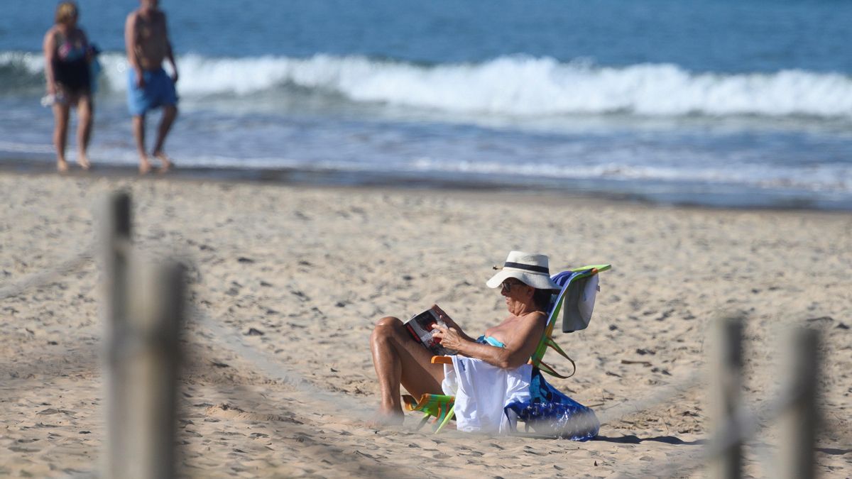 Una mujer disfruta del buen tiempo leyendo en una playa de Suances (Cantabria)