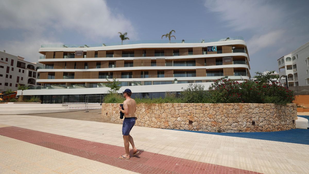 Un turista camina por el paseo marítimo de Santa Eulària frente a la promoción de 32 viviendas del puerto.