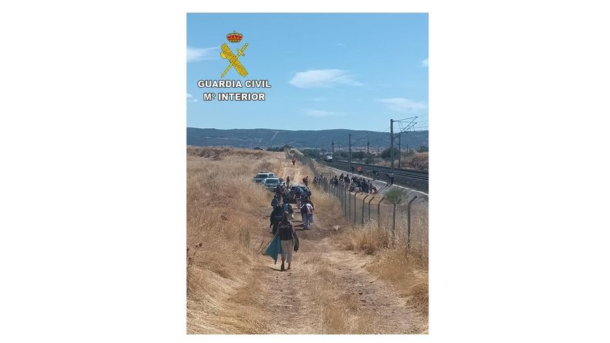 Pasajeros del tren con el vagón incendiado siendo evacuados por la Guardia Civil