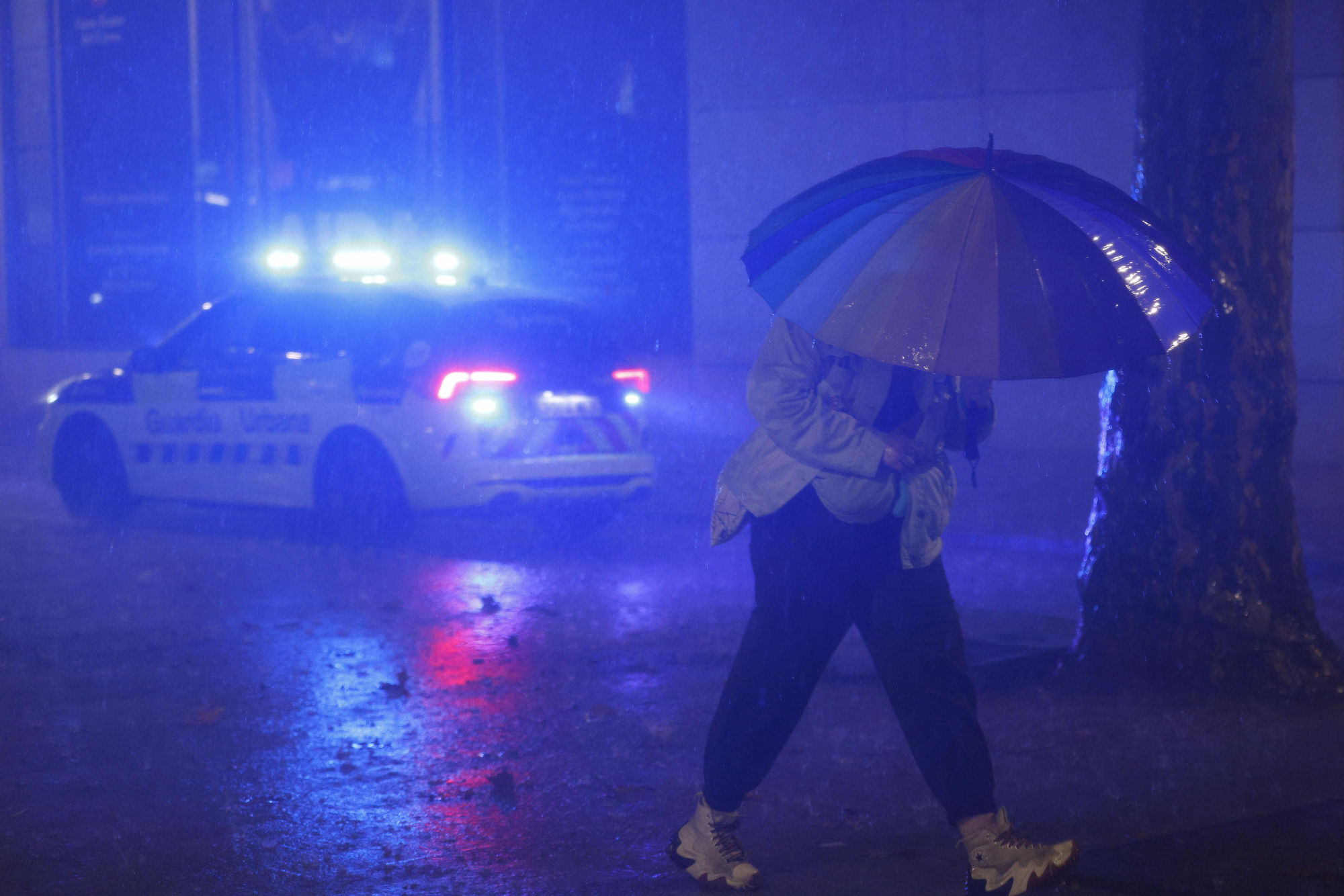 Un viandante protegiéndose de la intensa lluvia en Barcelona