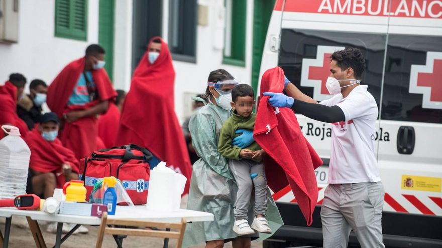 Un voluntario de la Cruz Roja abriga con una manta a uno de los niños llegados en una patera a la costa de Caleta de Caballo, en el norte de Lanzarote, en septiembre de 2020