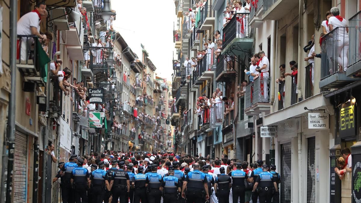 La policía municipal de Navarra organiza a los transeúntes antes del primer encierro de las fiestas de San Fermín en 2019.