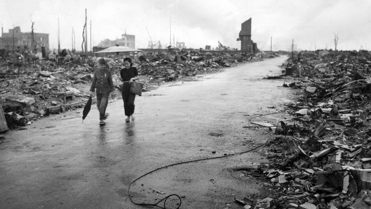 Dos jóvenes caminan por una calle flanqueada por escombros en la devastada Hiroshima, en 1945, primera ciudad en el mundo en sufrir los efectos del arma nuclear