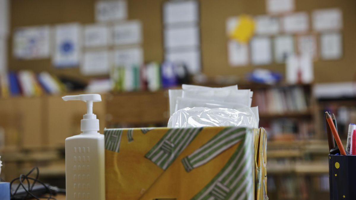 Mascarillas y gel desinfectante en la mesa del profesor de un aula escolar.