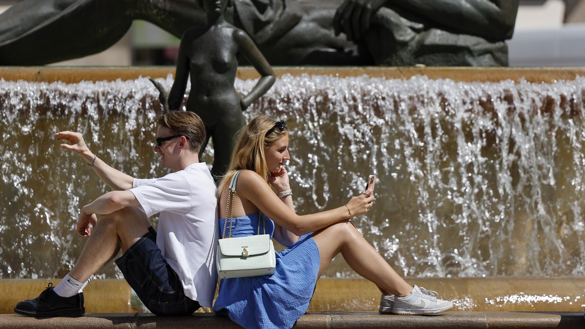 Dos turistas aguardan junto a una fuente