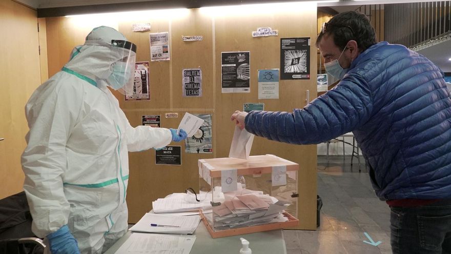 Un votante ejerce su derecho a voto en una mesa con sus miembros equipados con EPI