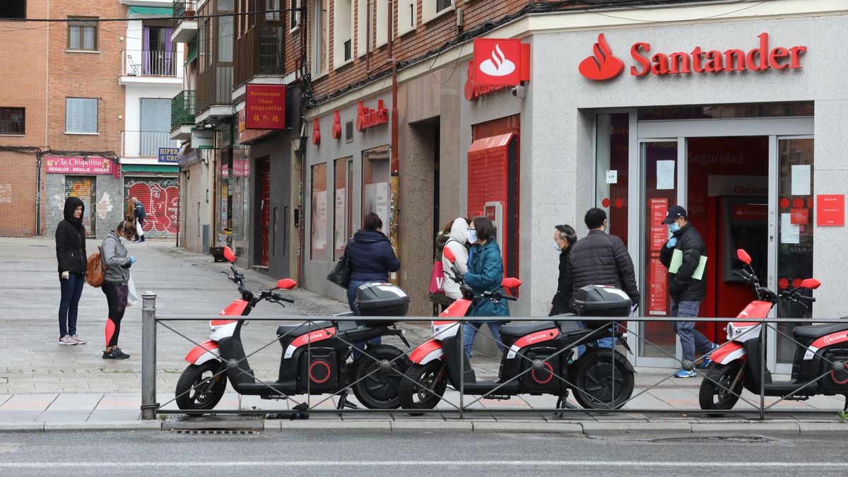 Varias personas esperan para entrar a una oficina del Banco Santander durante el inicio de la cuarta semana del estado de alarma decretado a consecuencia del coronavirus. En Madrid (España), a 6 de abril de 2020.