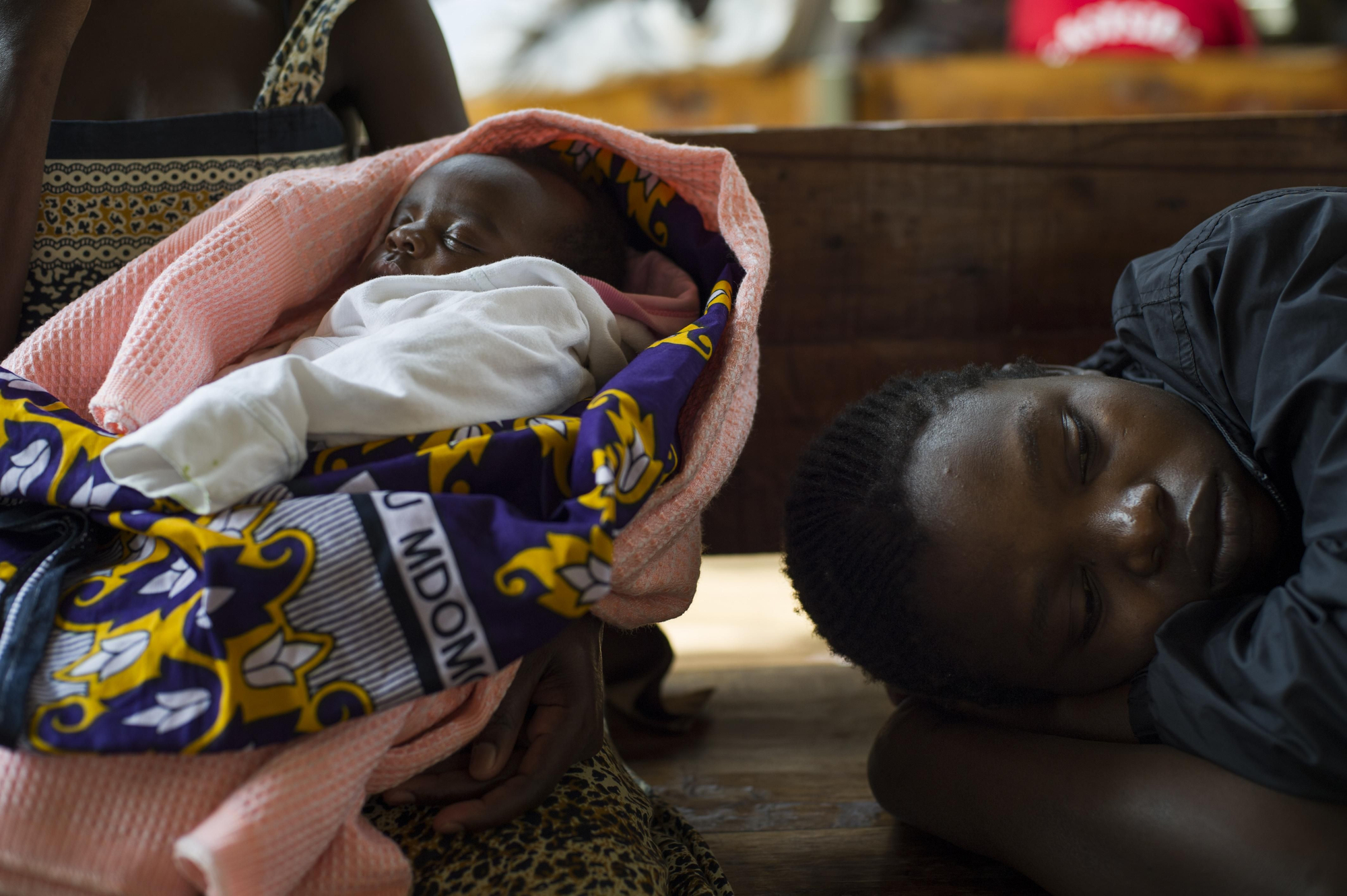 “He venido para vacunar a  mi hija. Soy una madre que vive con el virus del VIH desde 2008. En la clínica, donde me han ayudado a que mi bebé naciera libre del virus, he aprendido que ser VIH positiva no es el final de mi vida, que puedo dar a luz y hacer crecer a mi hija sana”, Caroline Ajiambo, 26 años sostiene a su bebé de seis semanas. Fotografía: Phil Moore
