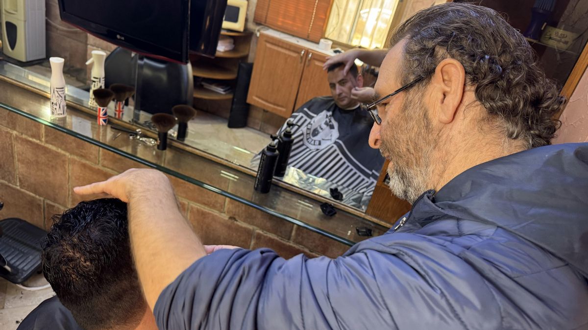 Abed Abderramán corta el pelo a Baraq Salum, excompañero de pupitre de Al-Sharaa, en su barbería del barrio Mezze Oriental.