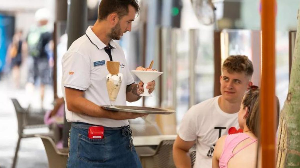 Un camarero, atendiendo a unos clientes en una terraza.