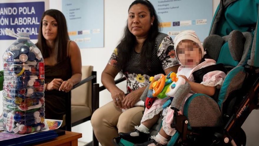 Alexia (d) un bebé de 25 meses de Ourense con parálisis cerebral infantil bilateral, acompañada por la trabajadora de la Fundación Amigos de Galicia, Paula Chapela (i) y su madre, Mayra López (c), este viernes durante la presentación de una campaña de recogida de tapones solidarios.