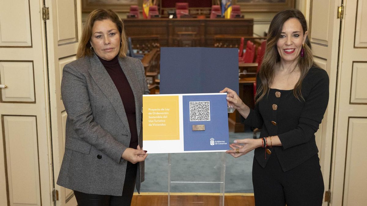 La consejera de Turismo y Empleo, Jéssica de León (derecha), entregando a la presidenta del Parlamento de Canarias, Astrid Pérez, el proyecto de ley de ordenación sostenible del uso turístico de viviendas para su tramitación por la Cámara Regional.
