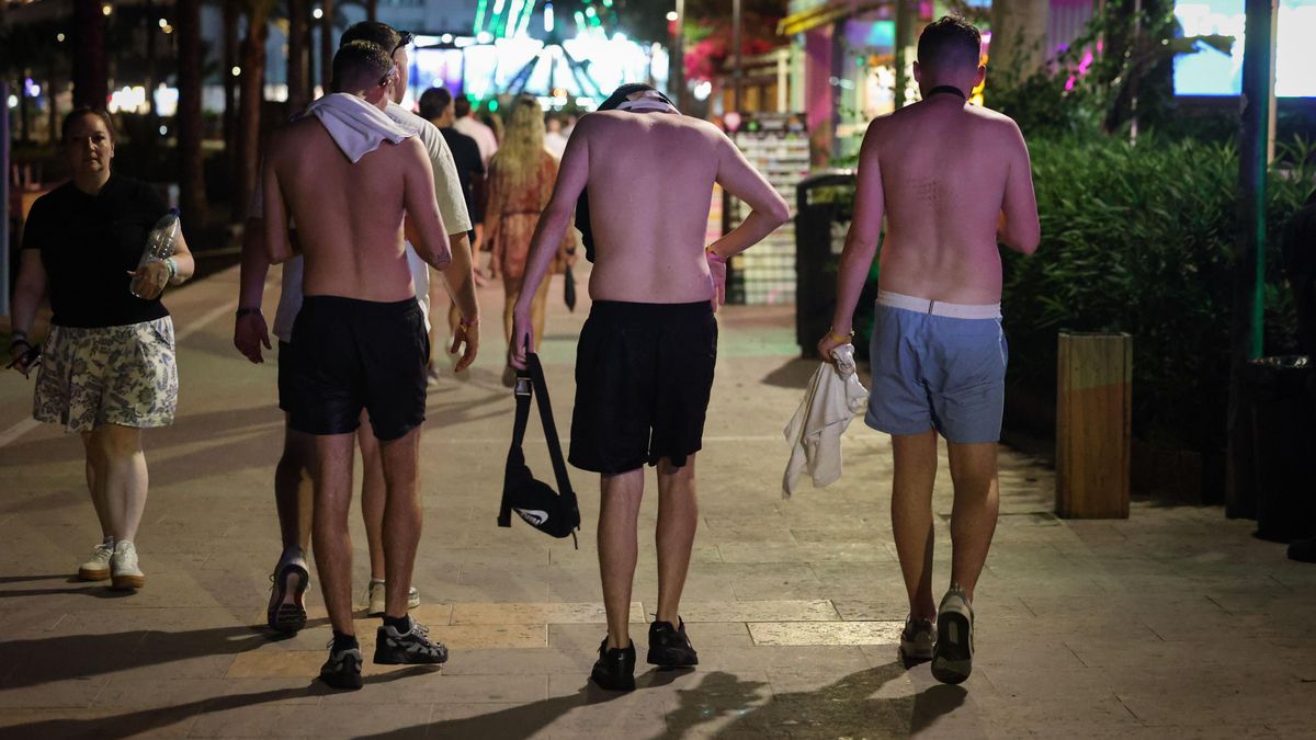 Tres turistes britànics caminen de nit sense samarreta pel passeig de s'Arenal de Sant Antoni.