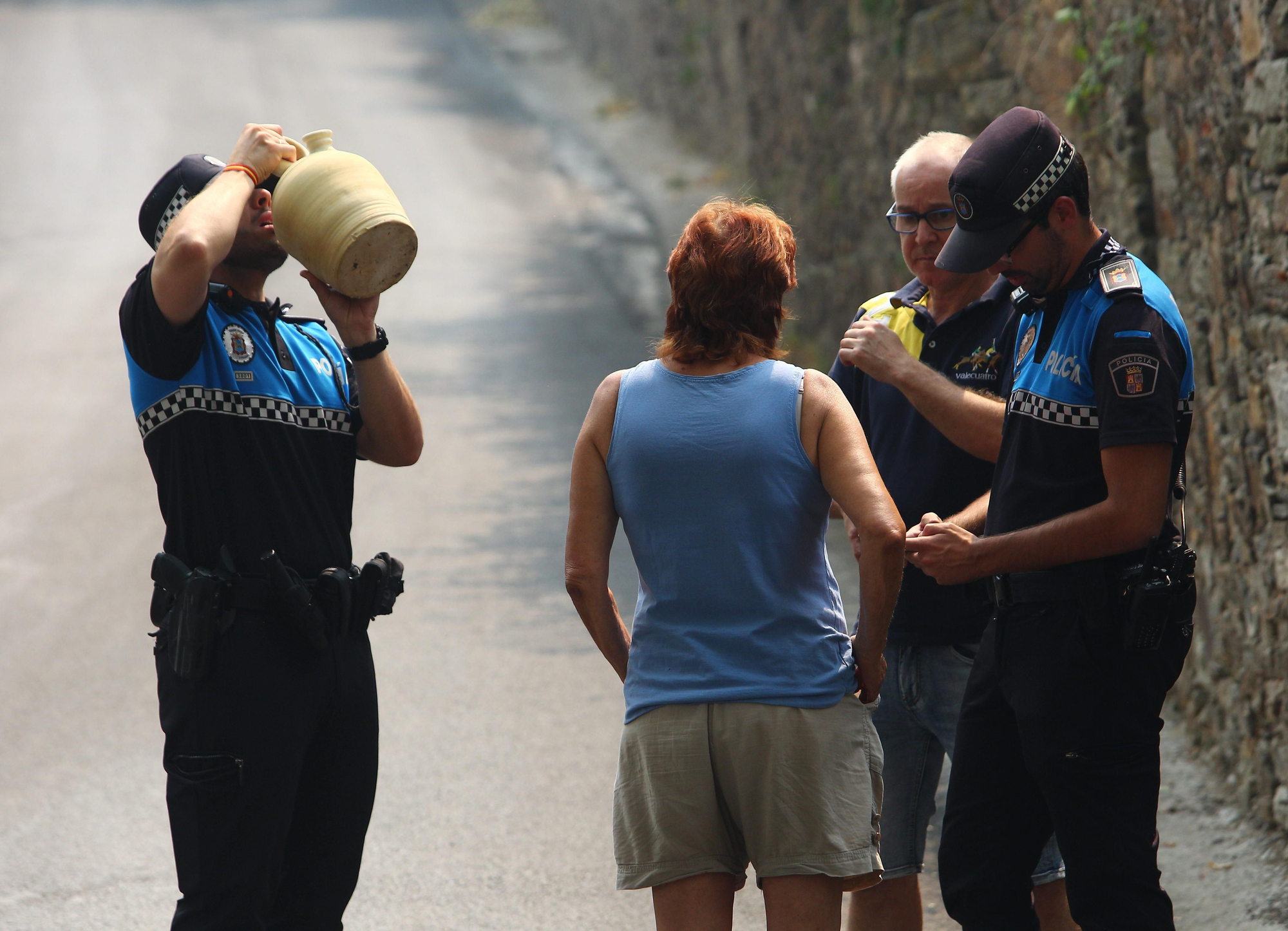 Vecinos y agentes de la Policía Local de Ponferrada intentando reponerse del calor, el fuego y la desolación que dejaron.