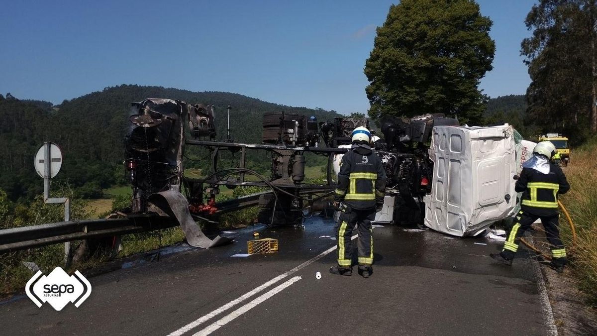 Los bomberos, en plena intervención junto al camión volcado a la altura de Colunga.