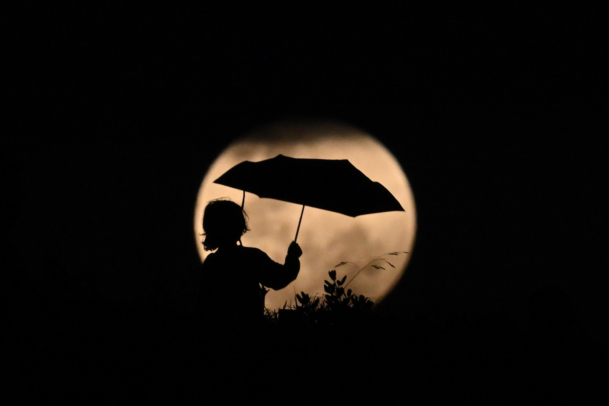 Un niño juega con un paraguas frente a la Luna, en Stanwell Park, al sur de Sidney.