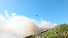 Un hidroavión descarga agua para sofocar un incendio forestal en Galicia.