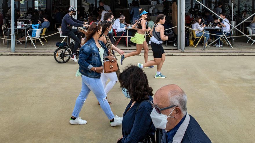 Varias personas pasean frente a un chiringuito del Paseo Marítimo de la Barceloneta hoy domingo, durante el primer día sin toque de queda en Cataluña. EFE/Enric Fontcuberta