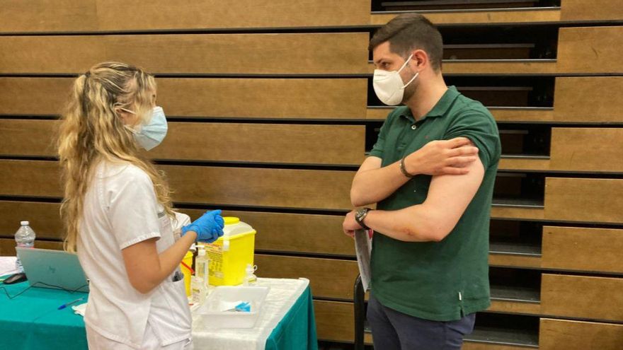 Una sanitaria dialoga con un joven después de ser vacunado contra el coronavirus en Gandia.