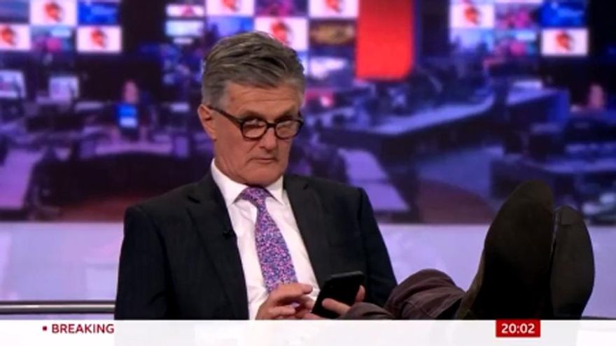 Pillan a un presentador de BBC News con el móvil y los pies encima de la mesa en pleno directo