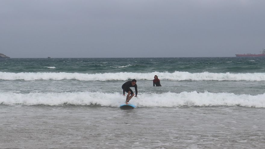 Juanma coge una ola ante la atenta mirada de Claudio, que sonríe orgulloso.