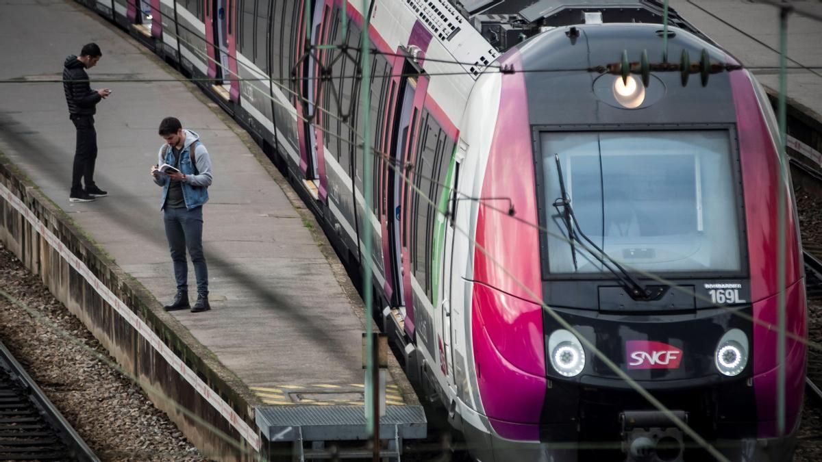 Varios usuarios aguardan en el andén de la estación de ferrocarril de Gare Saint Lazare, en París (Francia) junto a un tren de la empresa pública de ferrocarriles SNCF.