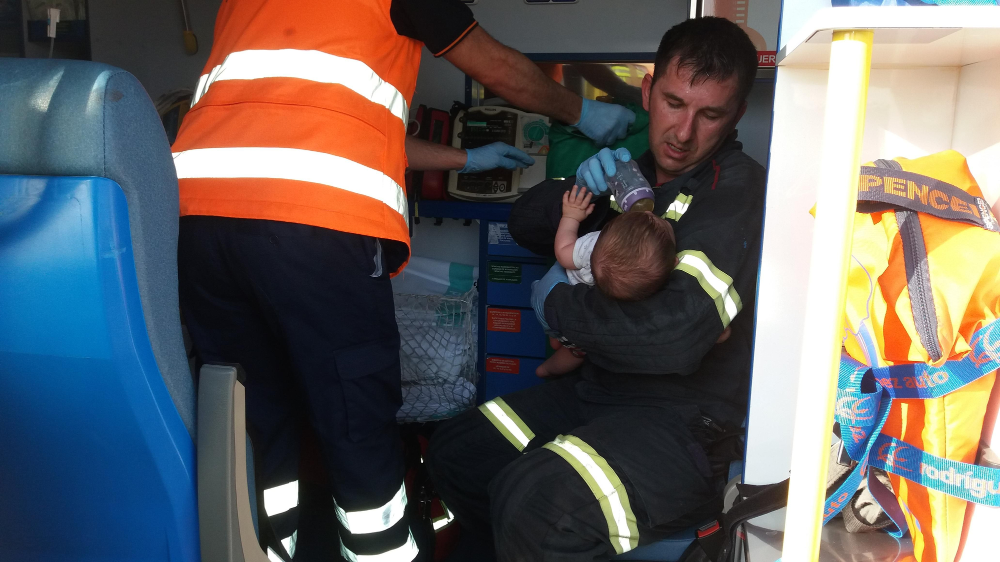 Un bombero de la DPZ, dando agua a un bebé tras un accidente en el que sus padres resultaron heridos graves.