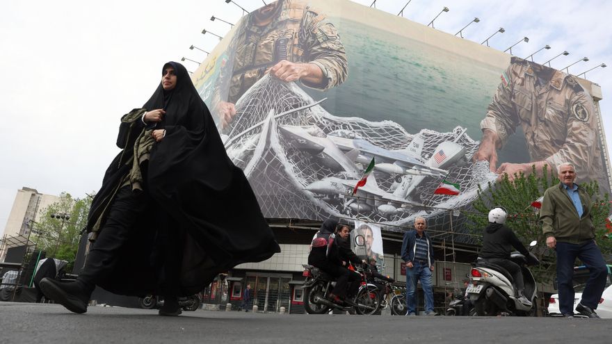 Una mujer camina el pasado domingo 12 de abril en Teherán ante un mural que reza en persa 'El estrecho de Ormuz seguirá cerrado', en la plaza Enghelab de la capital. EFE/EPA/ABEDIN TAHERKENAREH