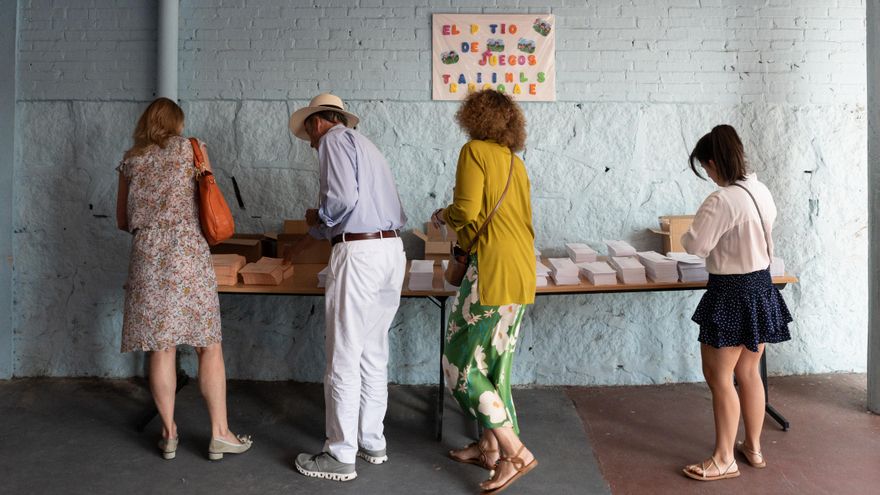 Varias personas cogen papeletas para ejercer su derecho a voto durante las elecciones generales de 2023, en el Colegio Ramiro de Maeztu.